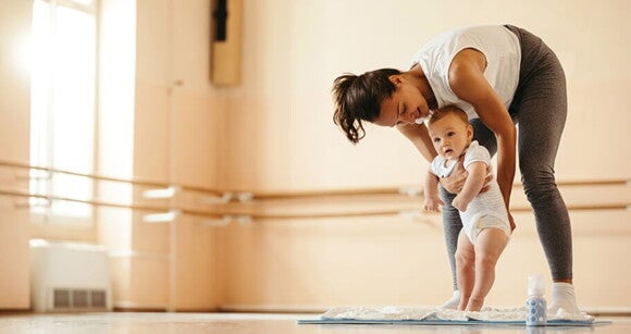 Mãe e bebê praticando sessão de yoga em uma sala na academia Mãe e bebê praticando sessão de yoga em uma sala na academia