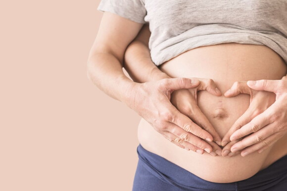 mulher com umbigo inflamado e mão em formato de coração na barriga mulher com umbigo inflamado e mão em formato de coração na barriga
