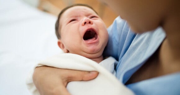 Mulher em um ambiente hospitalar com bebê chorando no colo Mulher em um ambiente hospitalar com bebê chorando no colo
