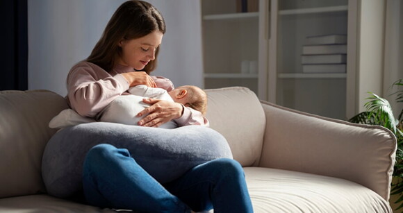 Mulher sentada no sofá amamentando seu bebê