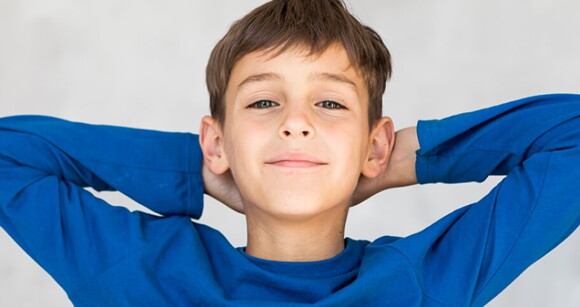 Menino vestindo camiseta de manga longa azul com as duas mãos na cabeça. Menino vestindo camiseta de manga longa azul com as duas mãos na cabeça.