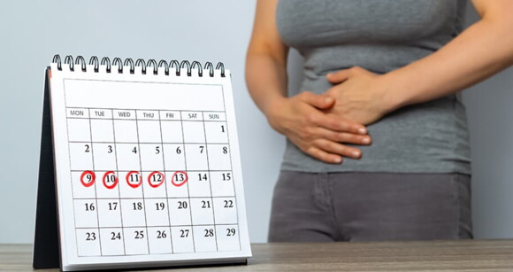 Imagem de calendário com dias riscados e mulher ao fundo com as duas mãos na barriga. Imagem de calendário com dias riscados e mulher ao fundo com as duas mãos na barriga.