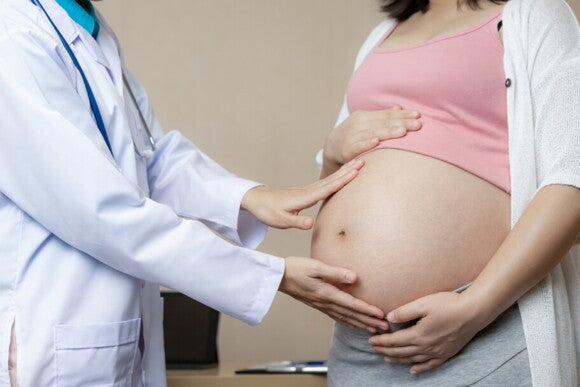 profissional de medicina com as mãos sob a barriga de uma gestante profissional de medicina com as mãos sob a barriga de uma gestante