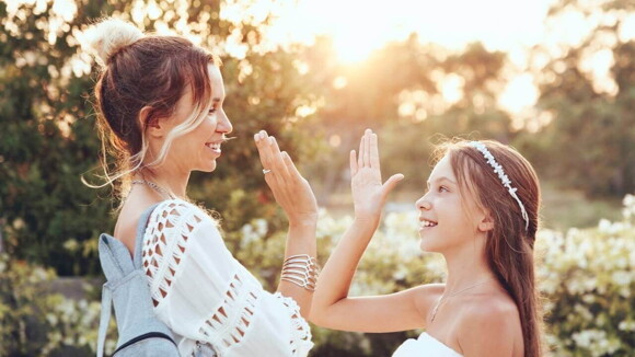 Uma menina e uma mulher com as mãos para cima em um cenário florido Uma menina e uma mulher com as mãos para cima em um cenário florido