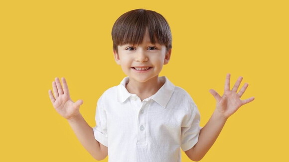 Menino sorrindo com as mãos abertas, sobre um fundo amarelo Menino sorrindo com as mãos abertas, sobre um fundo amarelo