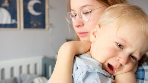 Bebê pequeno sendo confortado no colo de uma mulher, que parece preocupada. Bebê pequeno sendo confortado no colo de uma mulher, que parece preocupada.