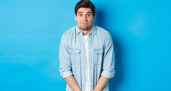Um homem com uma camisa jeans encostado em uma parede azul Um homem com uma camisa jeans encostado em uma parede azul