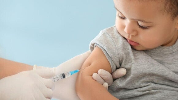 Criança pequena recebendo uma injeção no braço, aplicada por um profissional de saúde com luvas. Criança pequena recebendo uma injeção no braço, aplicada por um profissional de saúde com luvas.